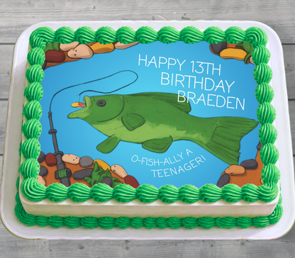 A square birthday cake decorated with green piped frosting around the border and a blue center panel showing a green fishing fish, rocks, and the text 'HAPPY 13TH BIRTHDAY BRAEDEN' and 'O-FISH-ALLY A TEENAGER!'.