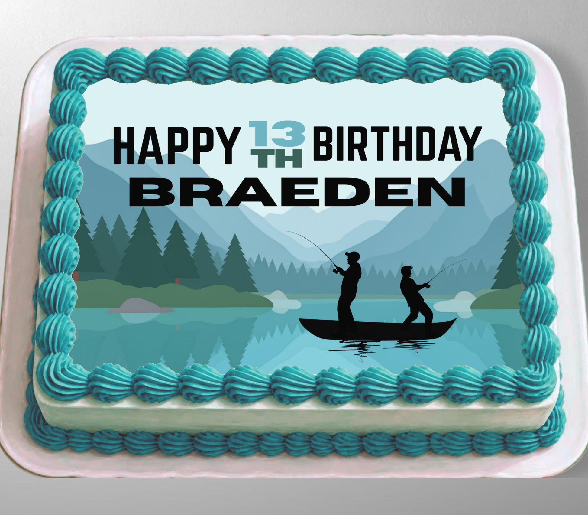 A rectangular cake with turquoise piped frosting borders and a printed top design showing a lake, mountains, trees, and two silhouetted people fishing. The top text reads “HAPPY 13TH BIRTHDAY BRAEDEN.