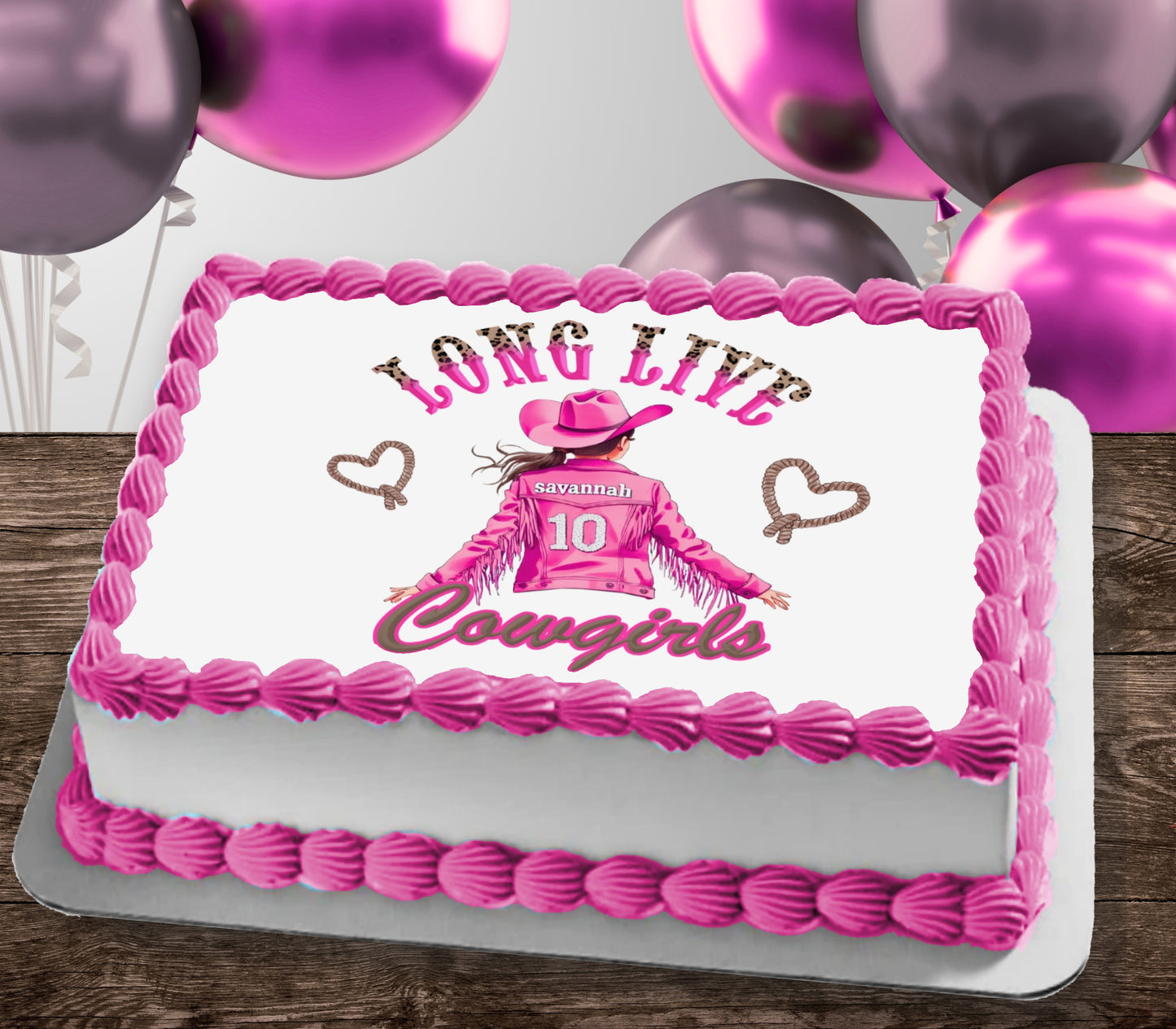 A rectangular white cake with pink piped frosting borders and a western-themed printed design on top. The design reads 'LONG LIVE Cowgirls' with a cowboy figure wearing a pink hat and jacket with the number 10.