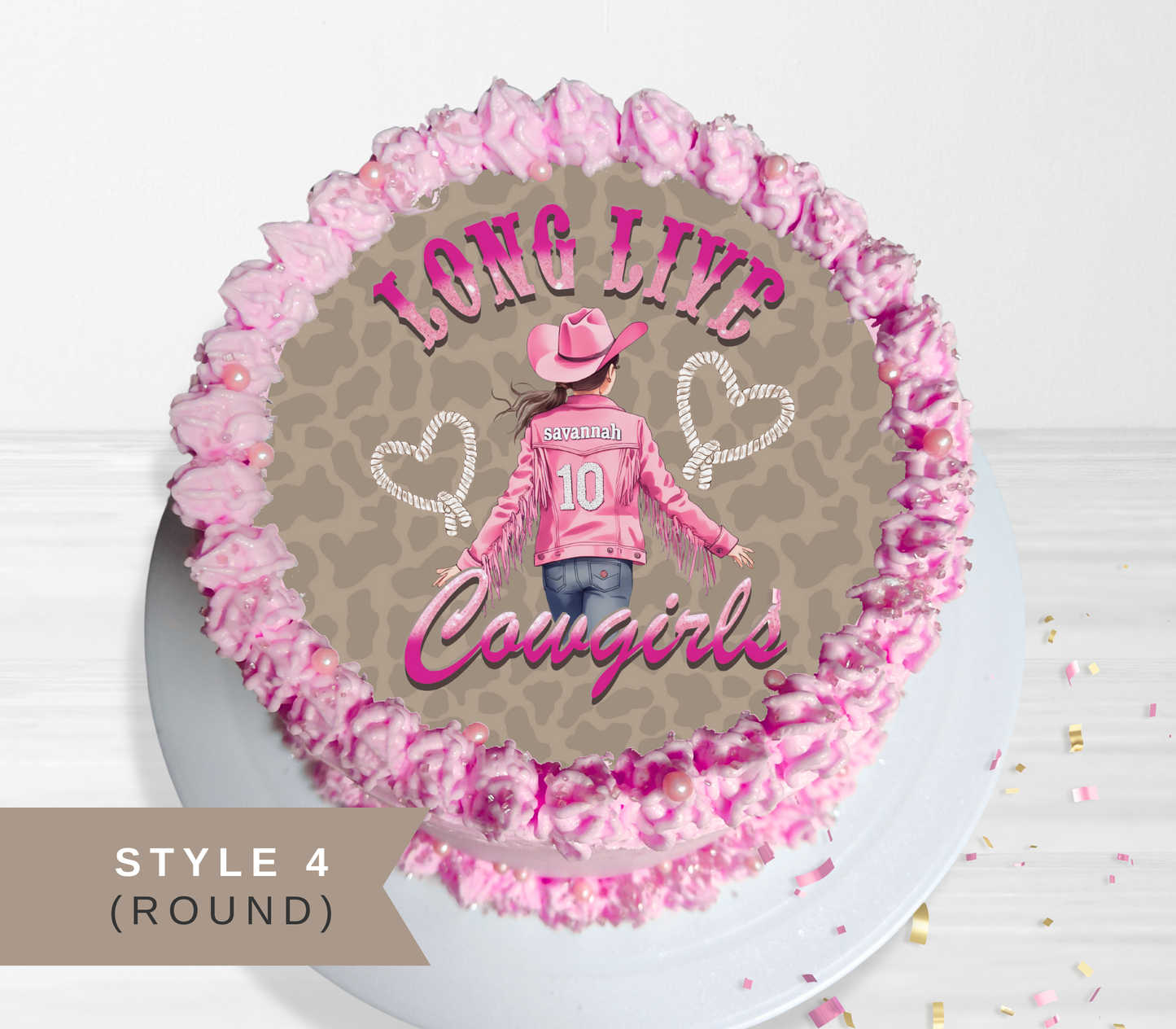 Round cake topper or cake decoration featuring a western cowgirl design with pink frosting piped around the edge, shown on a white plate against a light background. The design includes the words 'LONG LIVE Cowgirls' and a cowgirl illustration with a pink hat, pink jacket, jeans, and leopard-print background.
