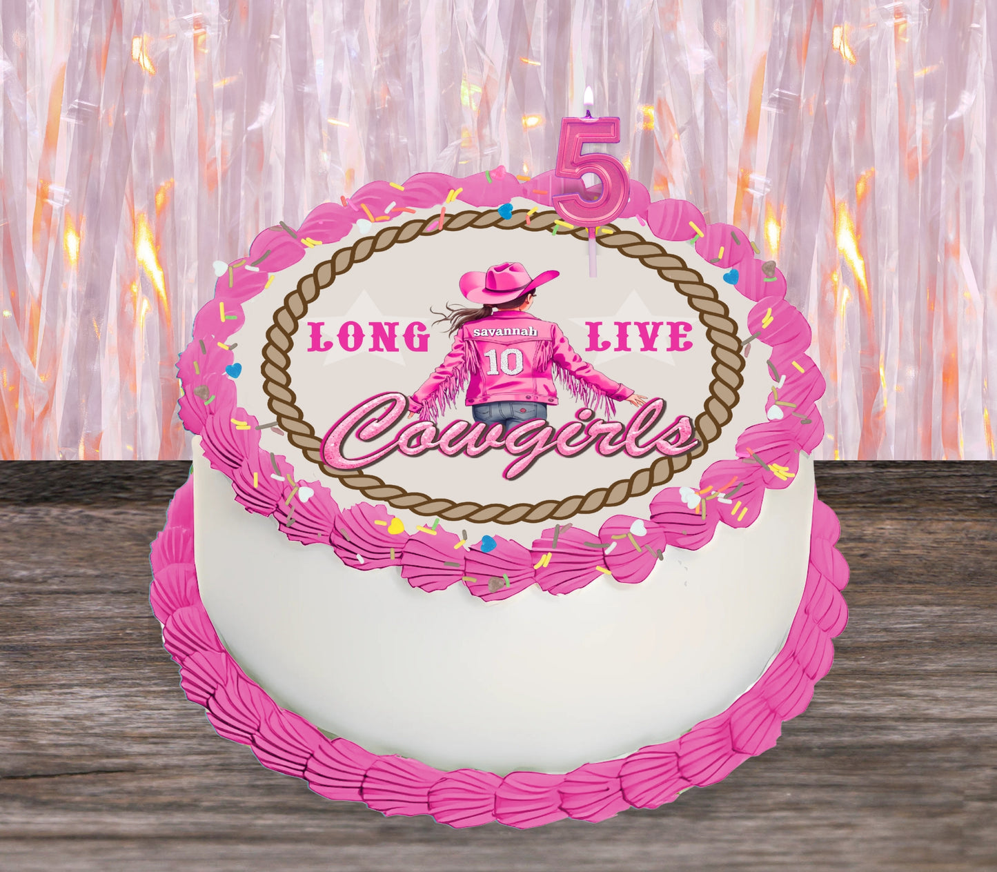 A round white birthday cake decorated with bright pink frosting piped borders and a central cowboy-themed design. The design includes the words 'LONG LIVE Cougars', a pink cowboy figure wearing a jacket with the number 10, and a pink number 5 candle on top.