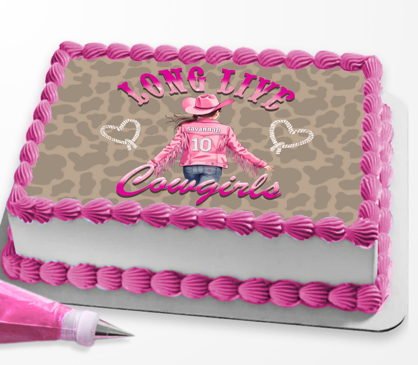 A rectangular cake decorated with pink piped frosting borders and a tan leopard-print top panel. The center graphic shows a woman in a pink cowboy outfit with the text 'LONG LIVE Cowgirls' and 'COUGAR' in script.