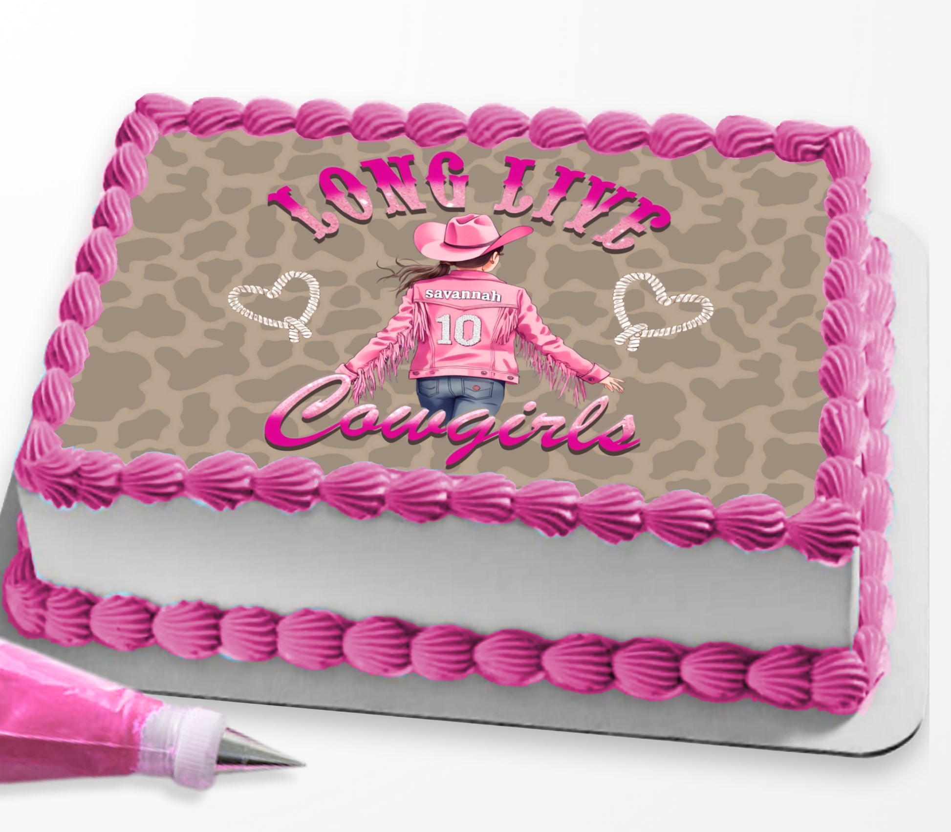 A rectangular cake decorated with pink piped frosting borders and a tan leopard-print top panel. The center graphic shows a woman in a pink cowboy outfit with the text 'LONG LIVE Cowgirls' and 'COUGAR' in script.